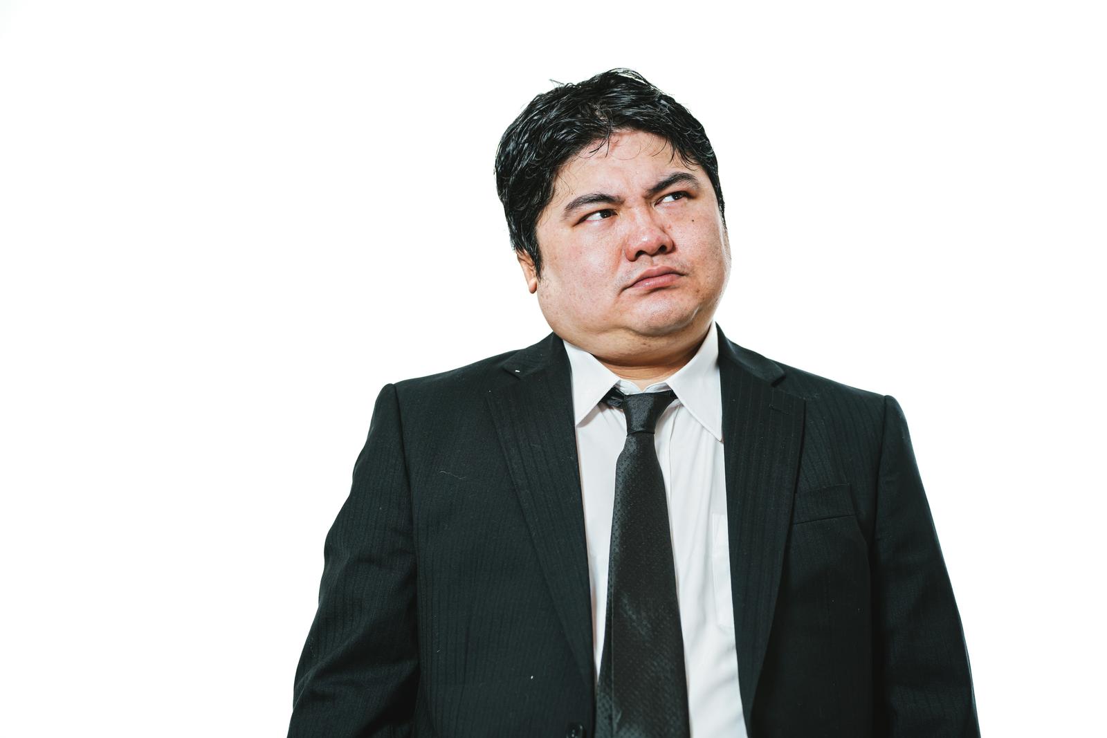 Heavyset male businessman in suit with gaze averted to the upper right, standing against white background