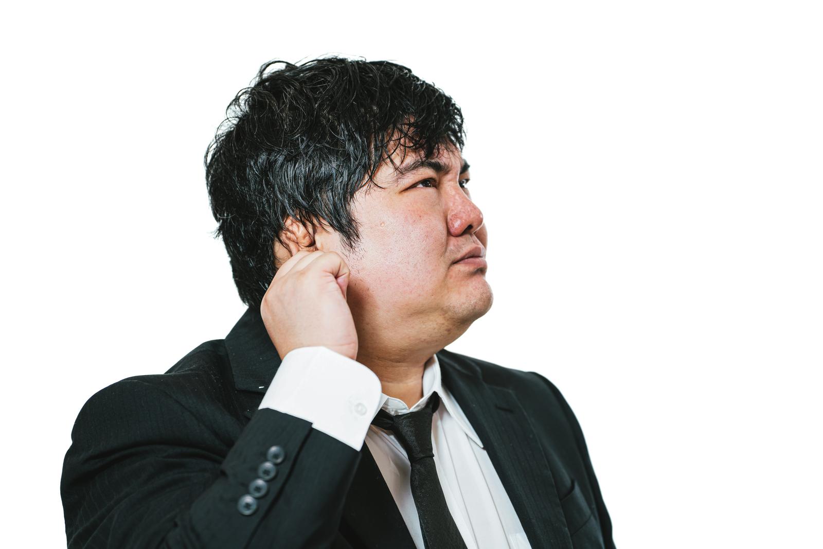 Troubled businessman in suit with hand on the back of his neck, looking upward against a white background