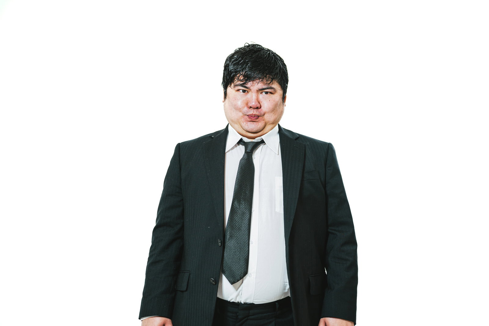 黒いスーツを着て口をつぐむ表情の男性会社員［モデル：段田隼人］