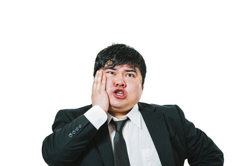 右の奥歯が痛すぎるスーツ姿の男性が頬に手を当てて困惑