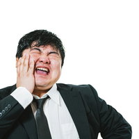 苦虫を噛み潰したような顔で頭を抱える男性会社員の写真