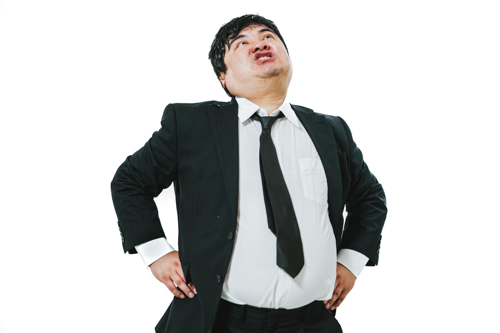 Low angle shot of an arrogant man in a business suit with hands on hips looking upward against a white background