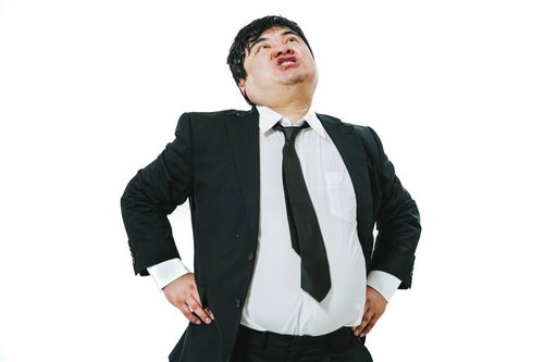 腰に手を当てて威張るスーツの男性