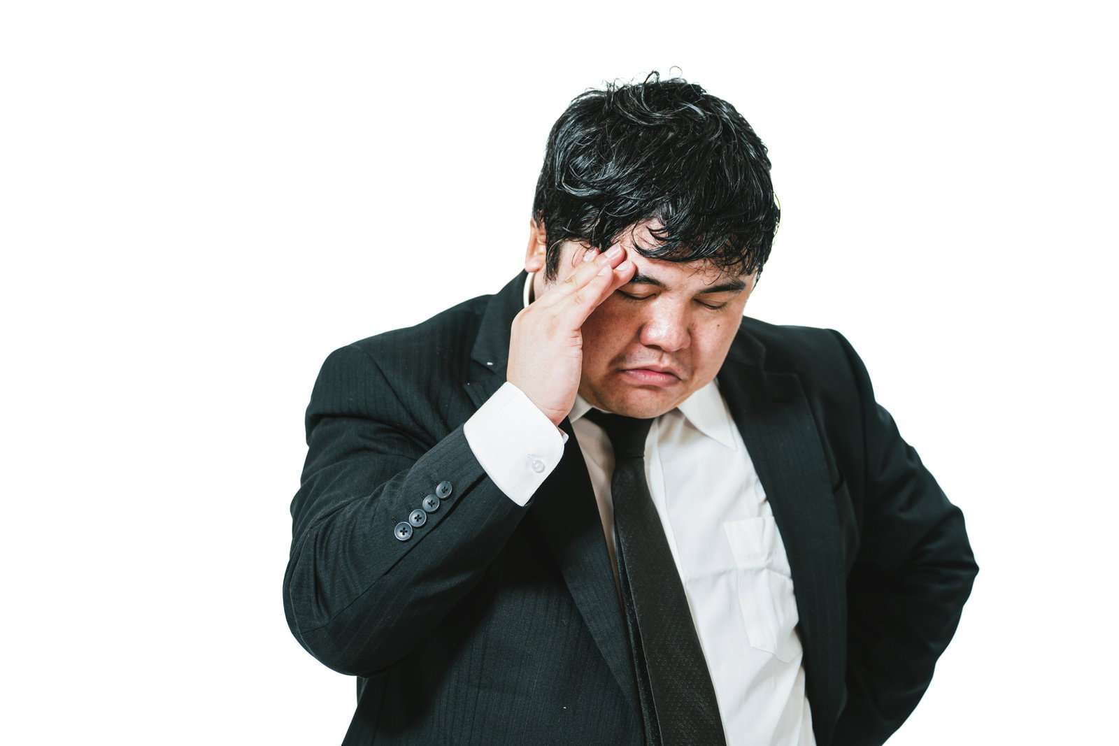 黒いスーツを着た男性が両手で頭を抱えて悩んでいる様子［モデル：段田隼人］