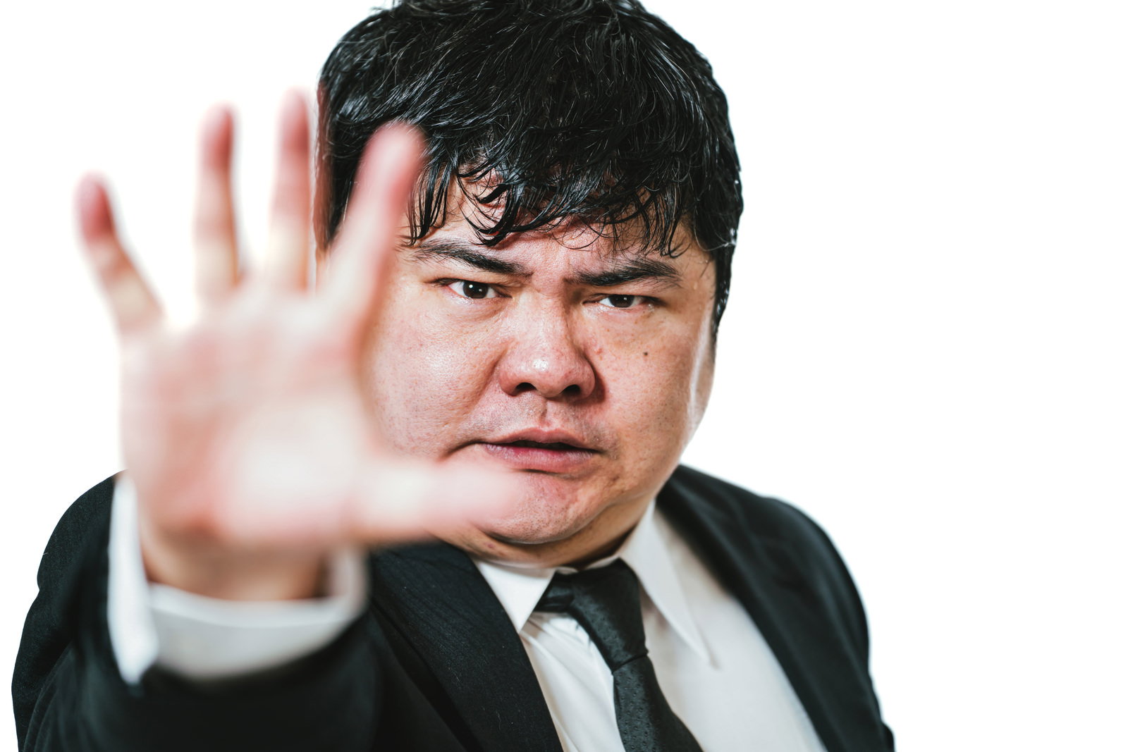 手のひらを前に向けてストップサインを示すスーツ姿のビジネスマン［モデル：段田隼人］