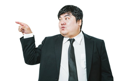 右側を指さして案内する会社員