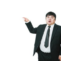 左方向を指さすスーツ姿の男性の写真