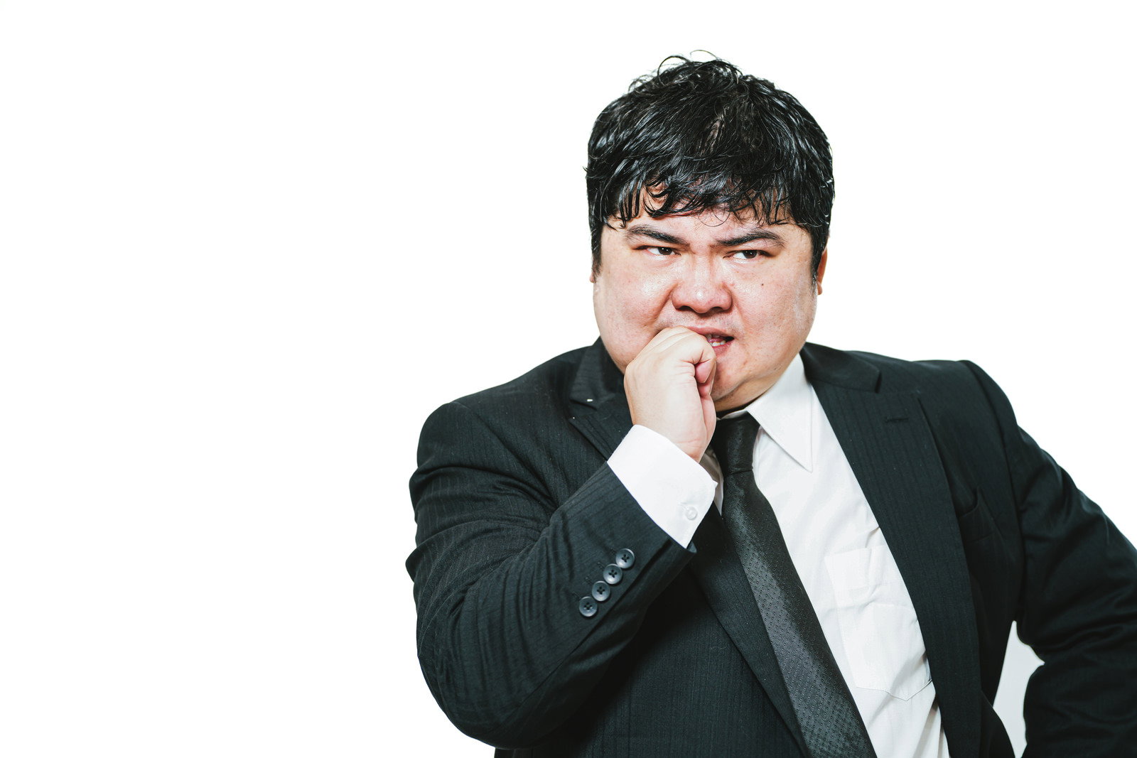 黒いスーツを着た男性が困った表情で爪を噛んでいる［モデル：段田隼人］