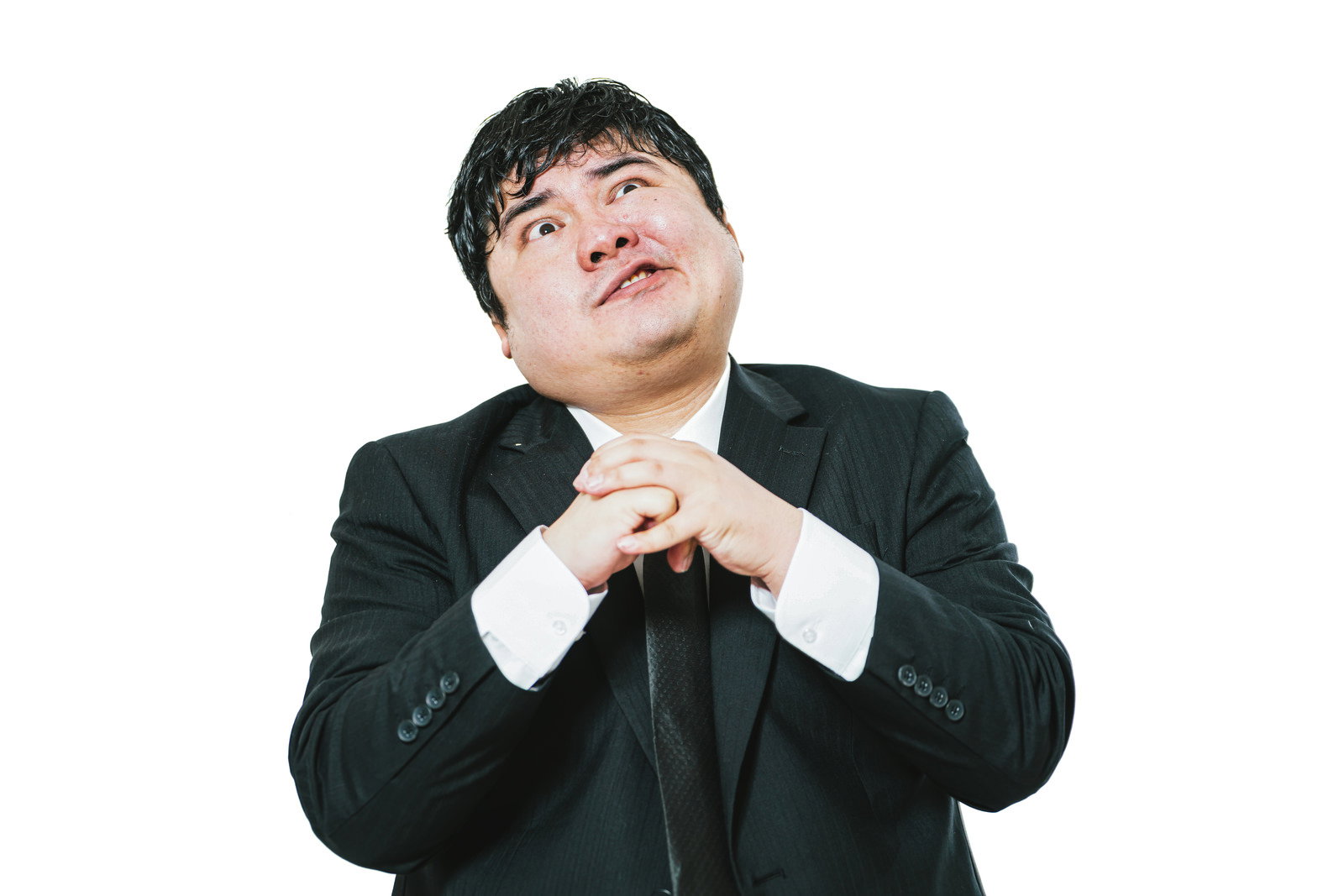 両手の拳を胸元で合わせ上目遣いで強気な顔を見せる黒スーツの男性［モデル：段田隼人］
