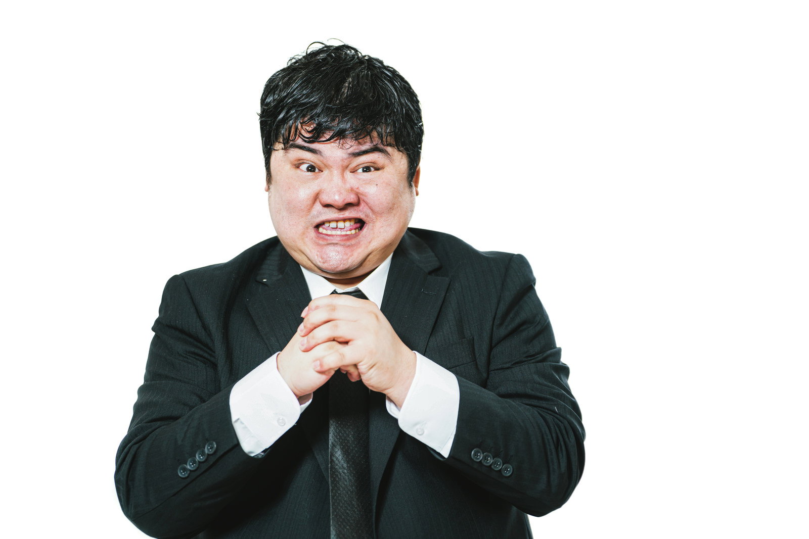 怒った表情でこぶしを握りしめるスーツ姿の男性［モデル：段田隼人］