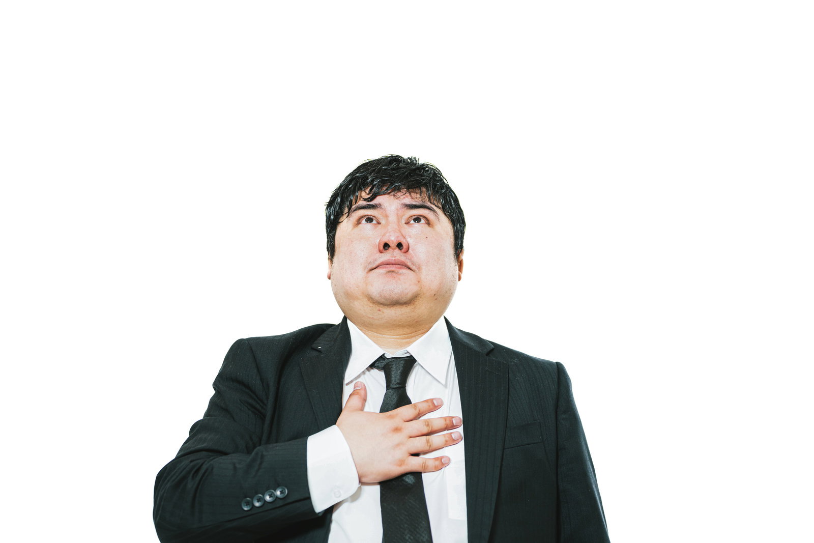 黒いスーツの男性が右手を胸に当て上を見上げて誓いを立てている［モデル：段田隼人］