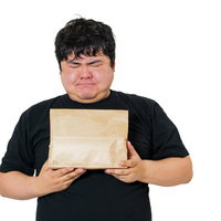 宅配物を受け取りながら考え込むユーザー男性の写真