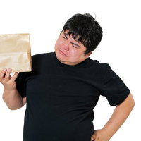 宅配物を片手に首をかしげる男性の戸惑う表情の写真