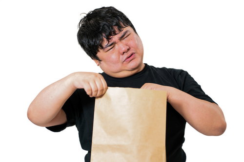 茶色い紙袋を両手で持ち、目をつむって中身を確認しようとする男性