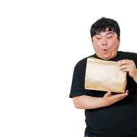 黒いTシャツ姿で茶色い紙袋を開封して驚く男性の表情の写真