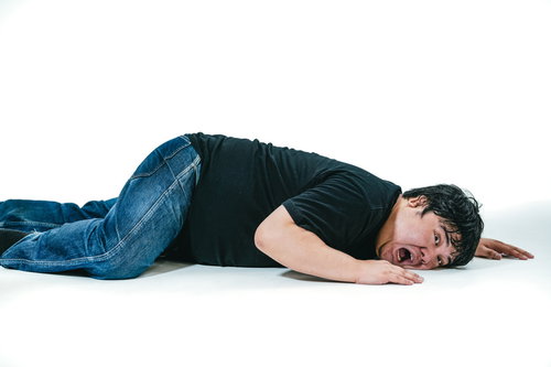 床に伏せて苦しむ表情の男性