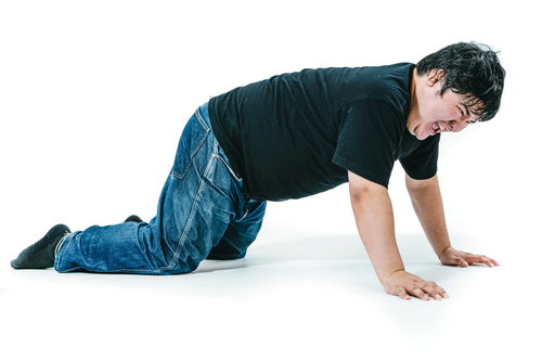 黒いTシャツとデニムで膝をついて立ち上がろうとする男性