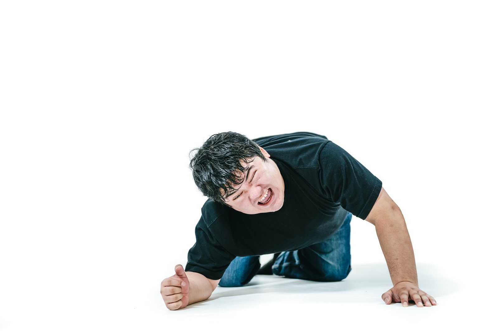 白背景のスタジオで床に両手をつき、悔しそうに歯を食いしばる黒シャツの男性［モデル：段田隼人］