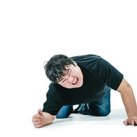 悔しさに拳を握り床に崩れる男性の写真