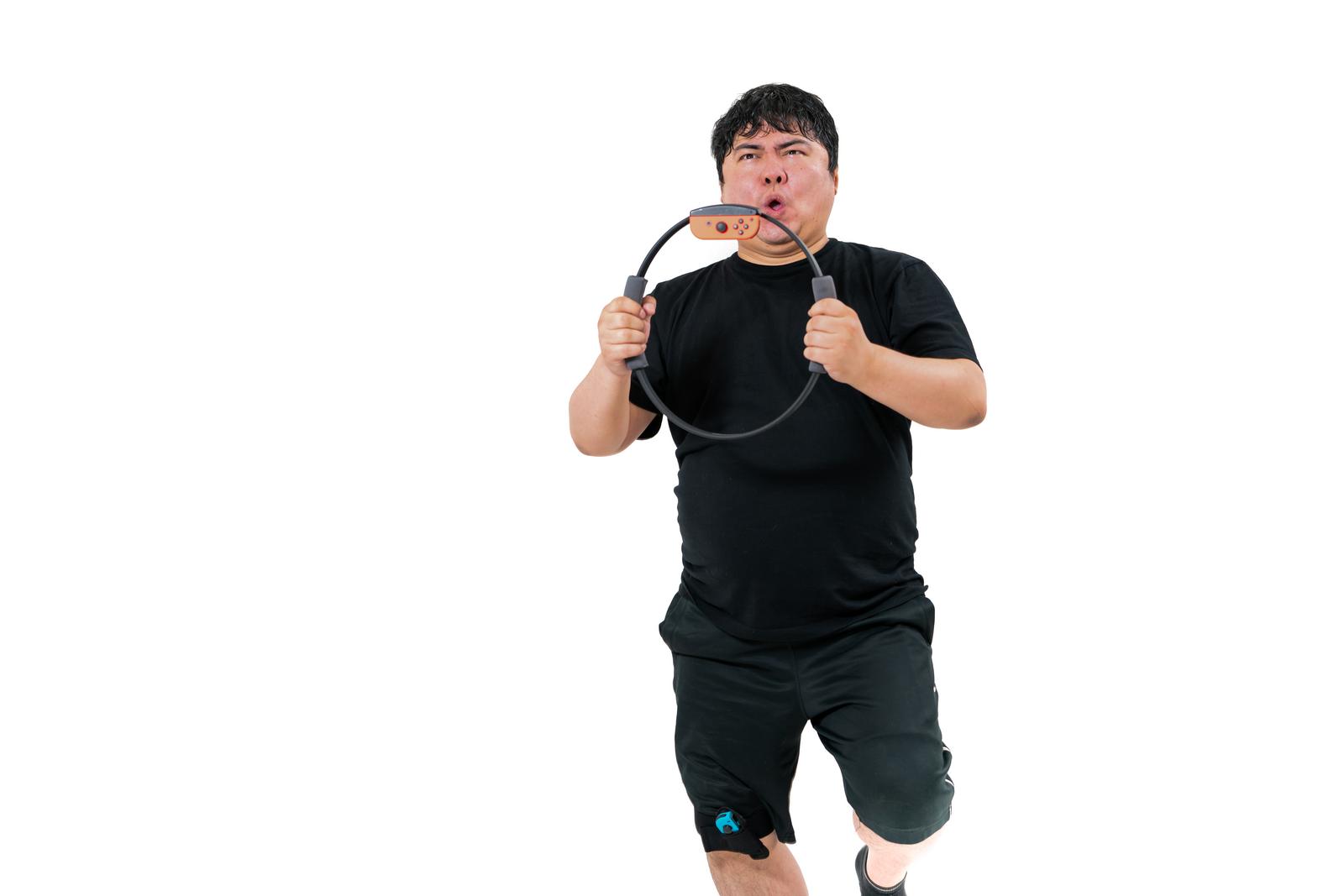 リングコンを両手で持ち走るポーズをとる黒い服のぽっちゃり男性［モデル：段田隼人］