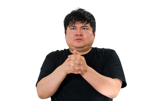 黒いTシャツを着て胸前で手を組み真剣な表情の男性