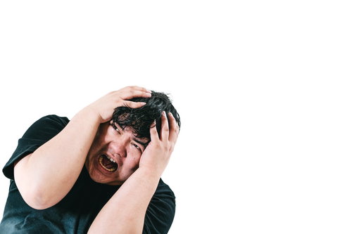 黒Tシャツ姿で両手で頭を抱えて叫ぶ男性