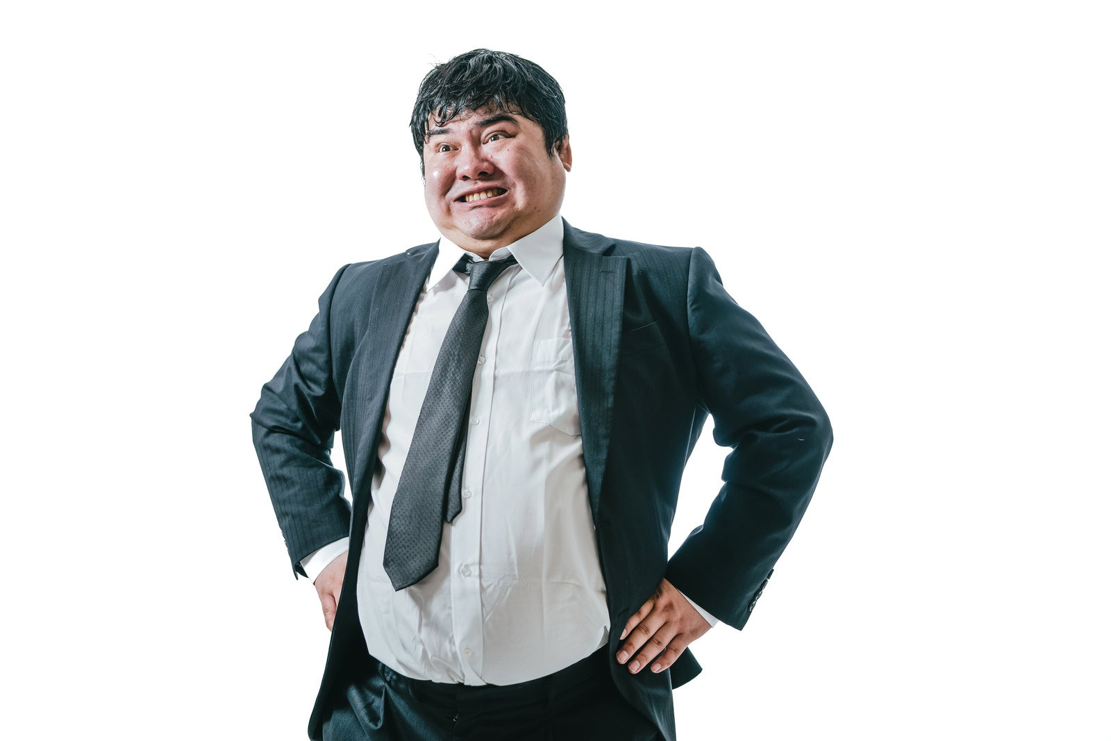 腰に手を当てて自信に満ちた表情で立つグレースーツの男性［モデル：段田隼人］
