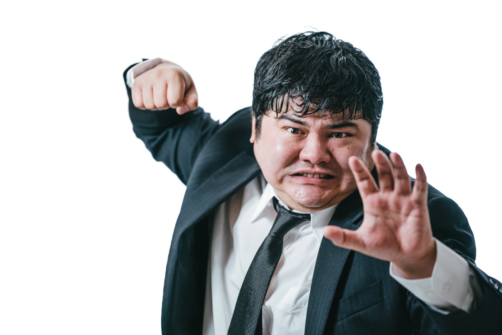 黒いスーツを着た男性が両手でパンチのポーズを取っている［モデル：段田隼人］