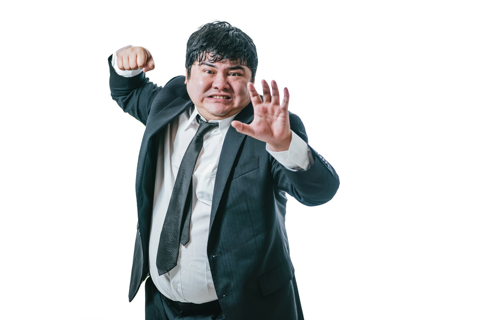 スーツを着た男性が怒った表情で拳を上げて構えている［モデル：段田隼人］