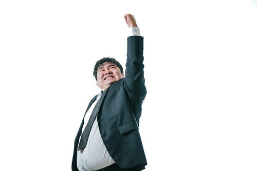 腕を大きく振り上げる男性会社員のガッツポーズ