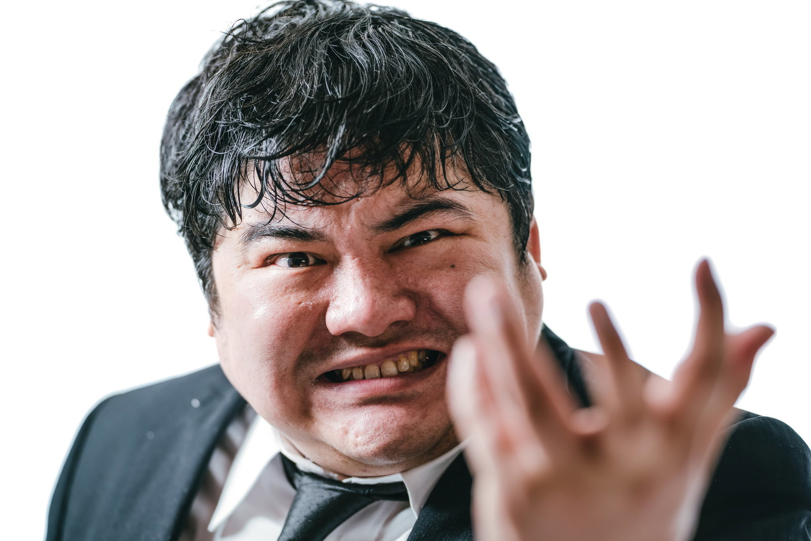 激しく怒る表情を見せるスーツ姿の会社員男性［モデル：段田隼人］
