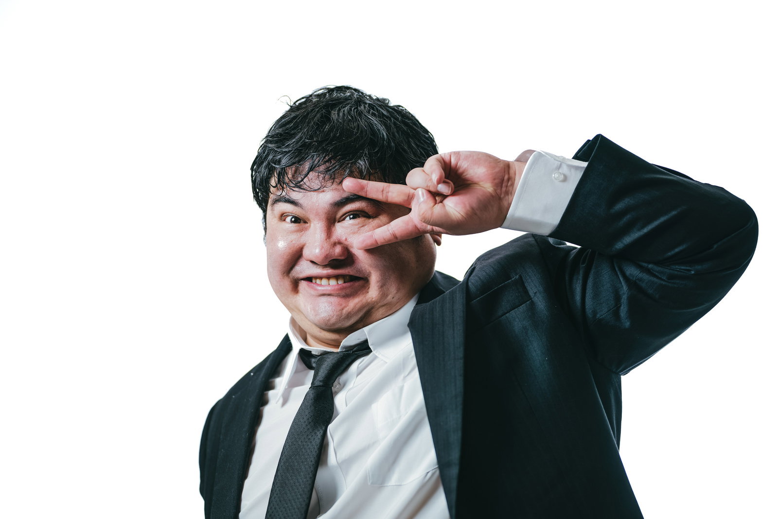 ピースサインをする笑顔のスーツ姿の男性［モデル：段田隼人］