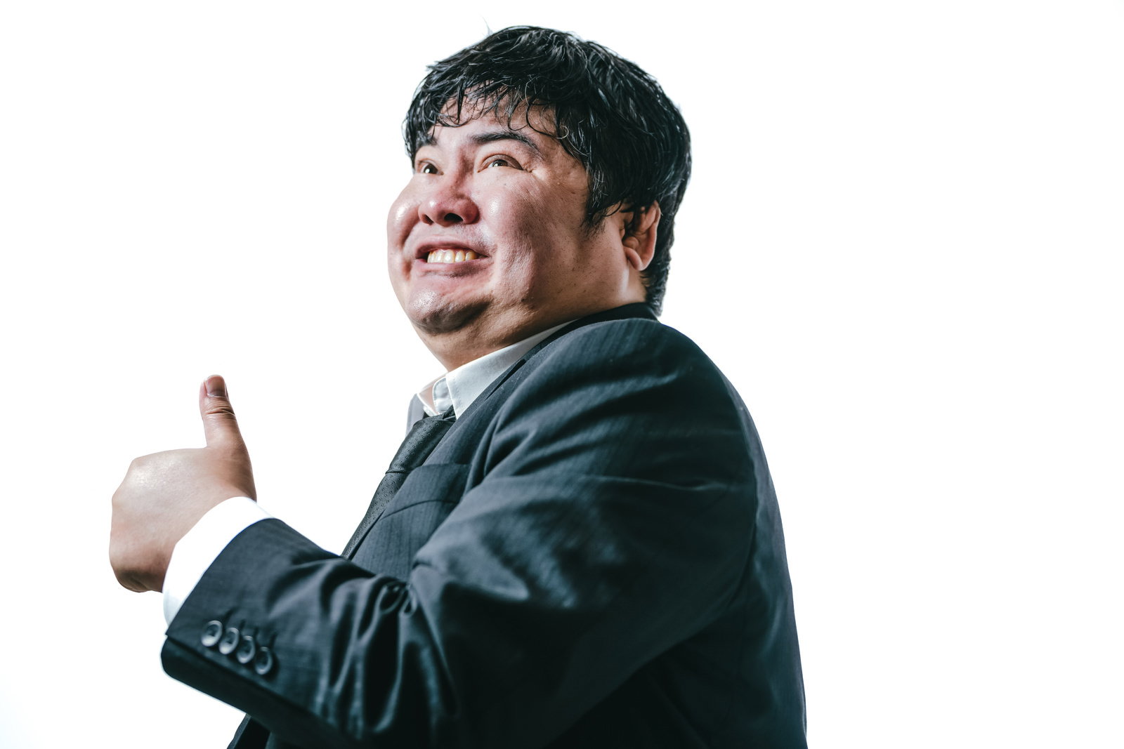 紺色のスーツを着た男性が笑顔で親指を立てている［モデル：段田隼人］