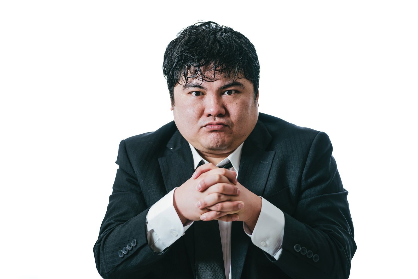 濃紺のスーツを着て手を組み緊張した表情を見せる会社員男性［モデル：段田隼人］