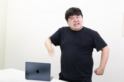 黒Tシャツの男性がノートパソコンに向かって腕を振り下ろす動作