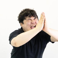 目を閉じて両手を合わせ懇願する黒いTシャツの男性の写真