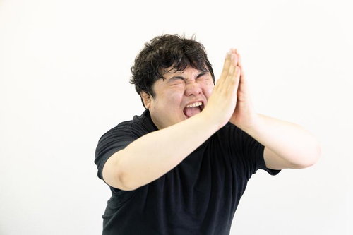 目を閉じて両手を合わせ懇願する黒いTシャツの男性