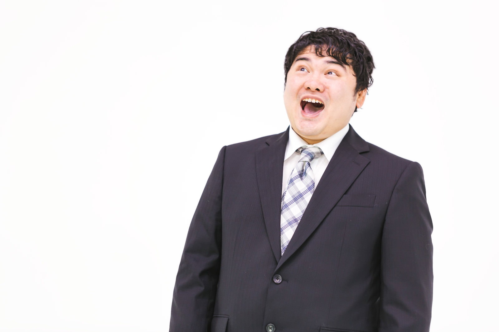 スーツ姿の男性が作り笑顔で誤魔化そうとしている様子［モデル：段田隼人］