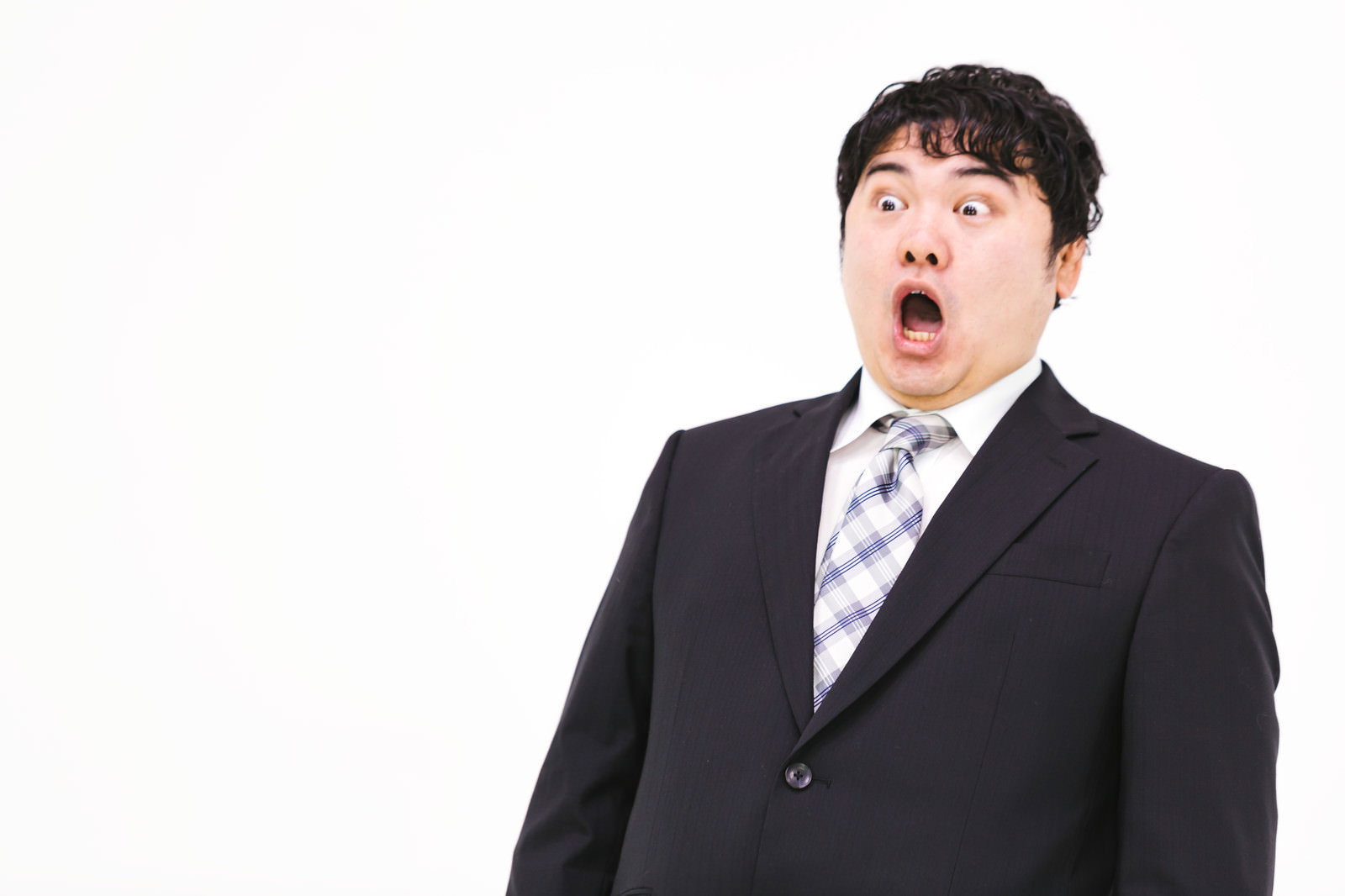 驚きの表情で体を反らせる黒いスーツ姿の営業マン［モデル：段田隼人］