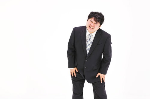 膝を痛めてしまった肥満男性のスーツ姿