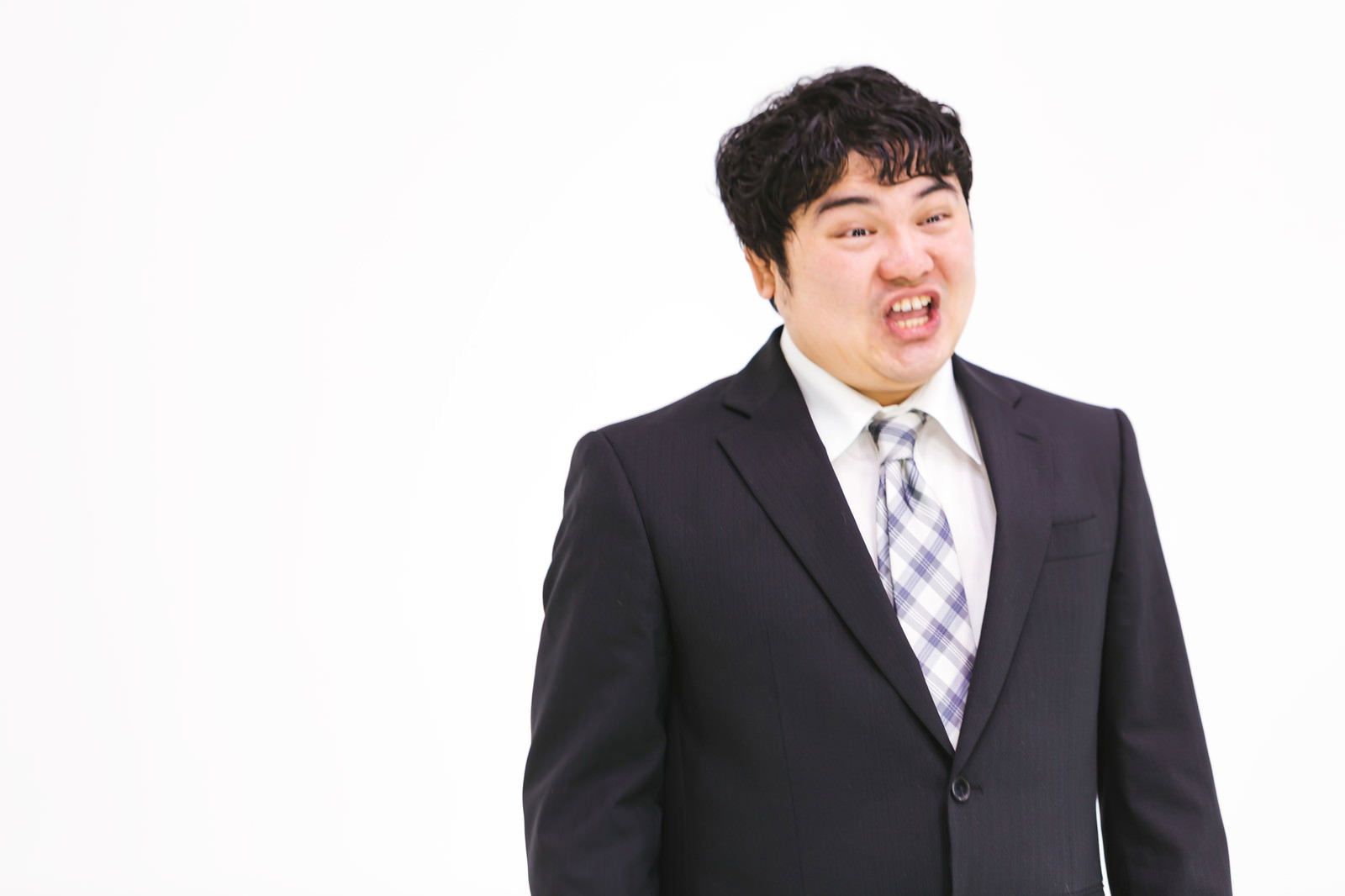 スーツ姿の男性が口を開けて怒声を上げている激怒表情［モデル：段田隼人］