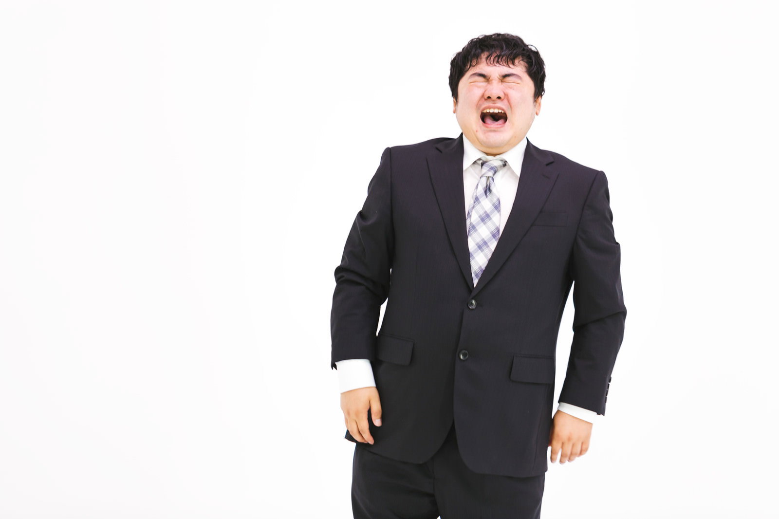 黒いスーツを着た会社員の男性が口を開けて泣いている表情［モデル：段田隼人］