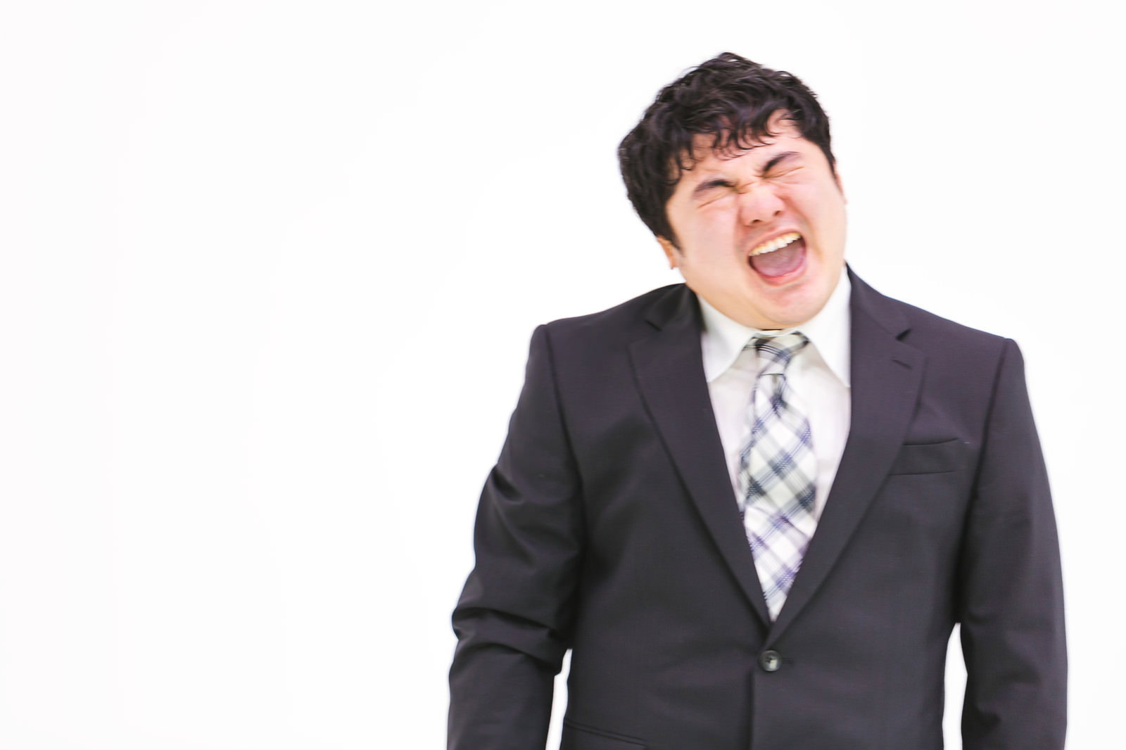 濃紺スーツと紫系ネクタイを着た男性が目を閉じて大きく口を開いて叫んでいる［モデル：段田隼人］