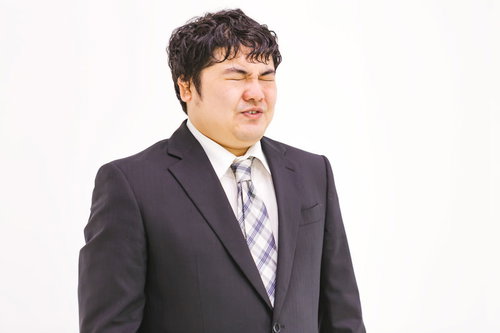 苦渋の色を浮かべるスーツ姿の会社員男性のビジネスポートレート