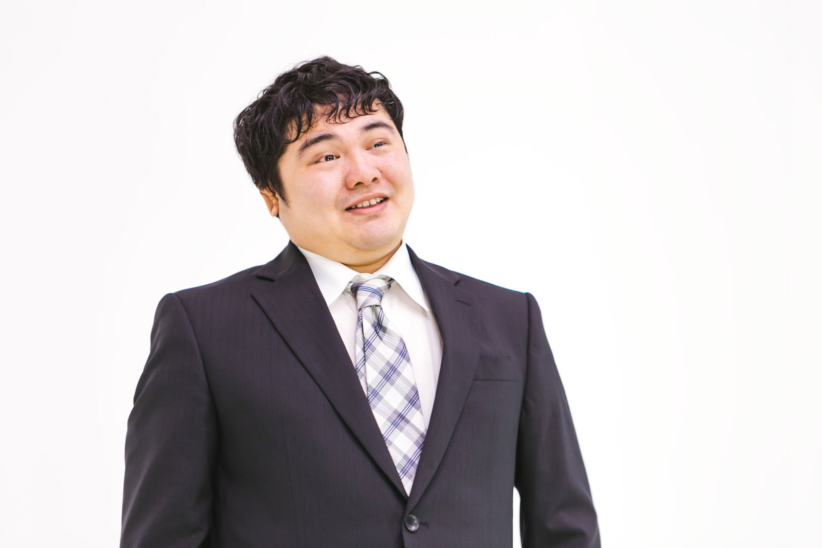 スーツネクタイ姿で相手を見下すような表情の男性が斜め上を向いている［モデル：段田隼人］