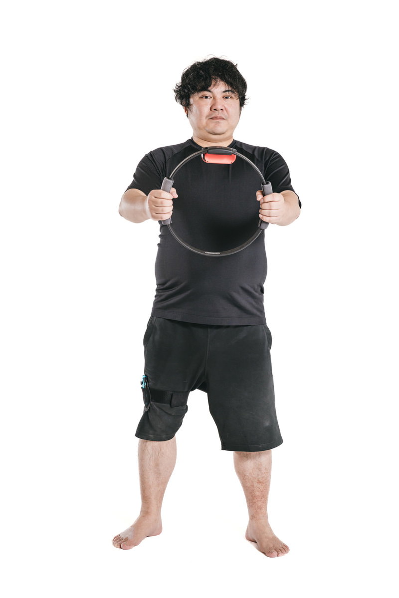 リングフィットを持つダイエット中の男性がフィットネストレーニングを行っている［モデル：段田隼人］