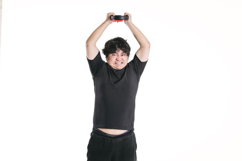 バンザイでリングコンを押さえるトレーニング姿の男性