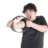 必死の形相で弓矢のポーズをとってトレーニングする男性の写真