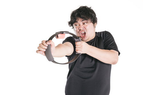 必死の形相で弓矢のポーズをとってトレーニングする男性