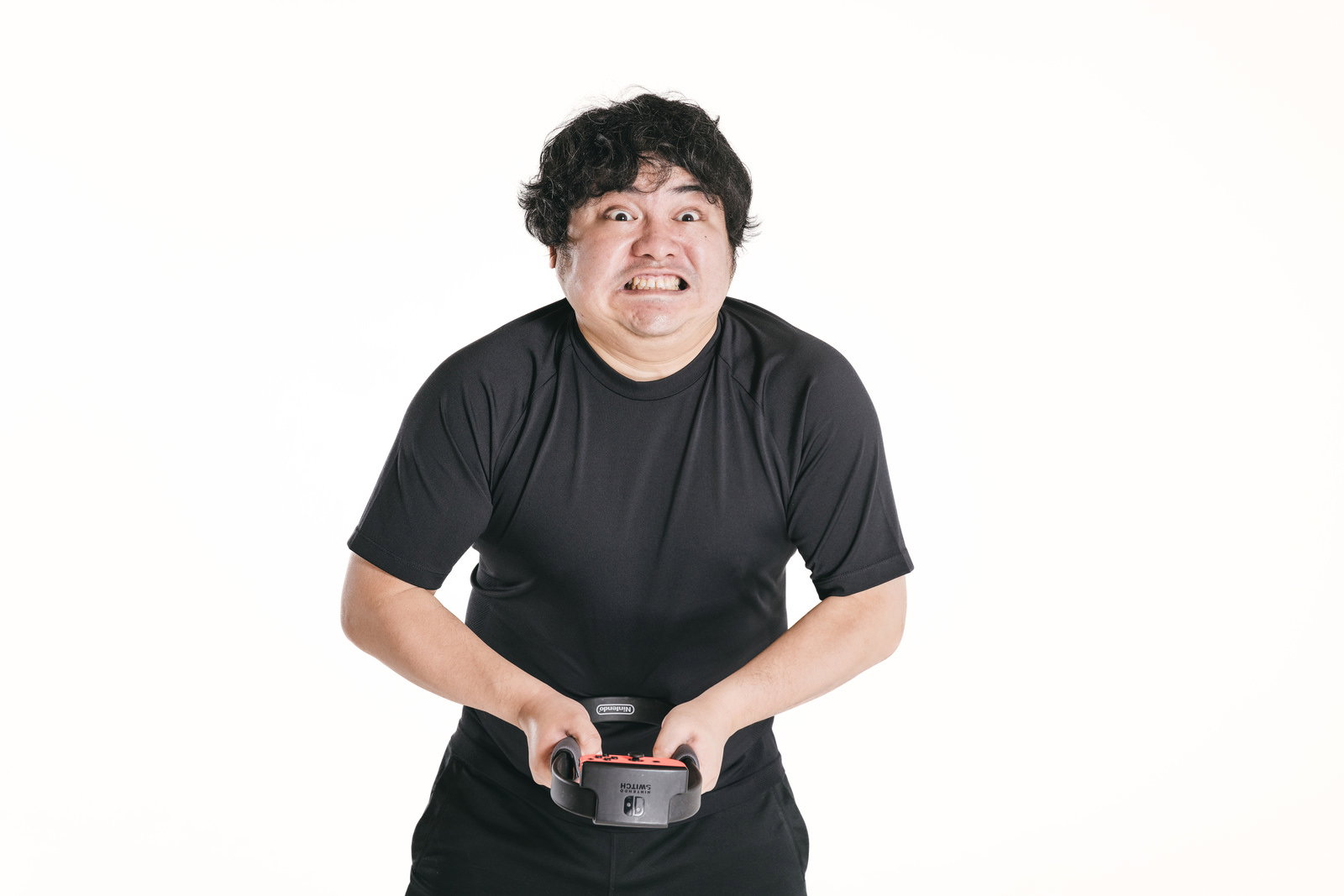 ゲームコントローラーを握って真剣な表情でプッシュする男性［モデル：段田隼人］